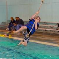 Boy swinging into pool on a rope swing