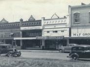 Bungalow Theater, M&F Grocery and Moore Drug about 1943, photo of buildings front with cars passing in front 