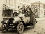 A carload of girls in front of the Cosy Theater in the early 1900's, all smiling and laughing