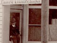 Hung Kee, owner of Chinese Laundry, 152 Garfield Street in 1900 - he is leaning against the front of the business under its sign