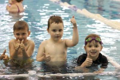 Three boys giving thumbs up in pool