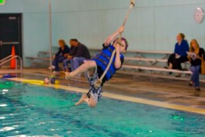 Boy swinging into pool on a rope swing